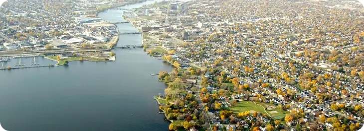 A scenic city view featuring a river flowing through, surrounded by lush green trees