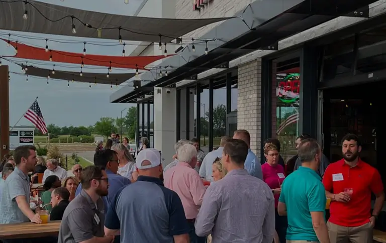 A lively group of individuals standing in front of a restaurant, engaged in conversation and enjoying the atmosphere